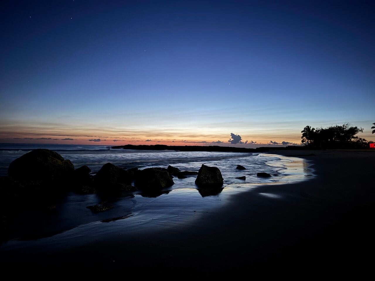dark blues and greys of a dawn over rocks abd ocean