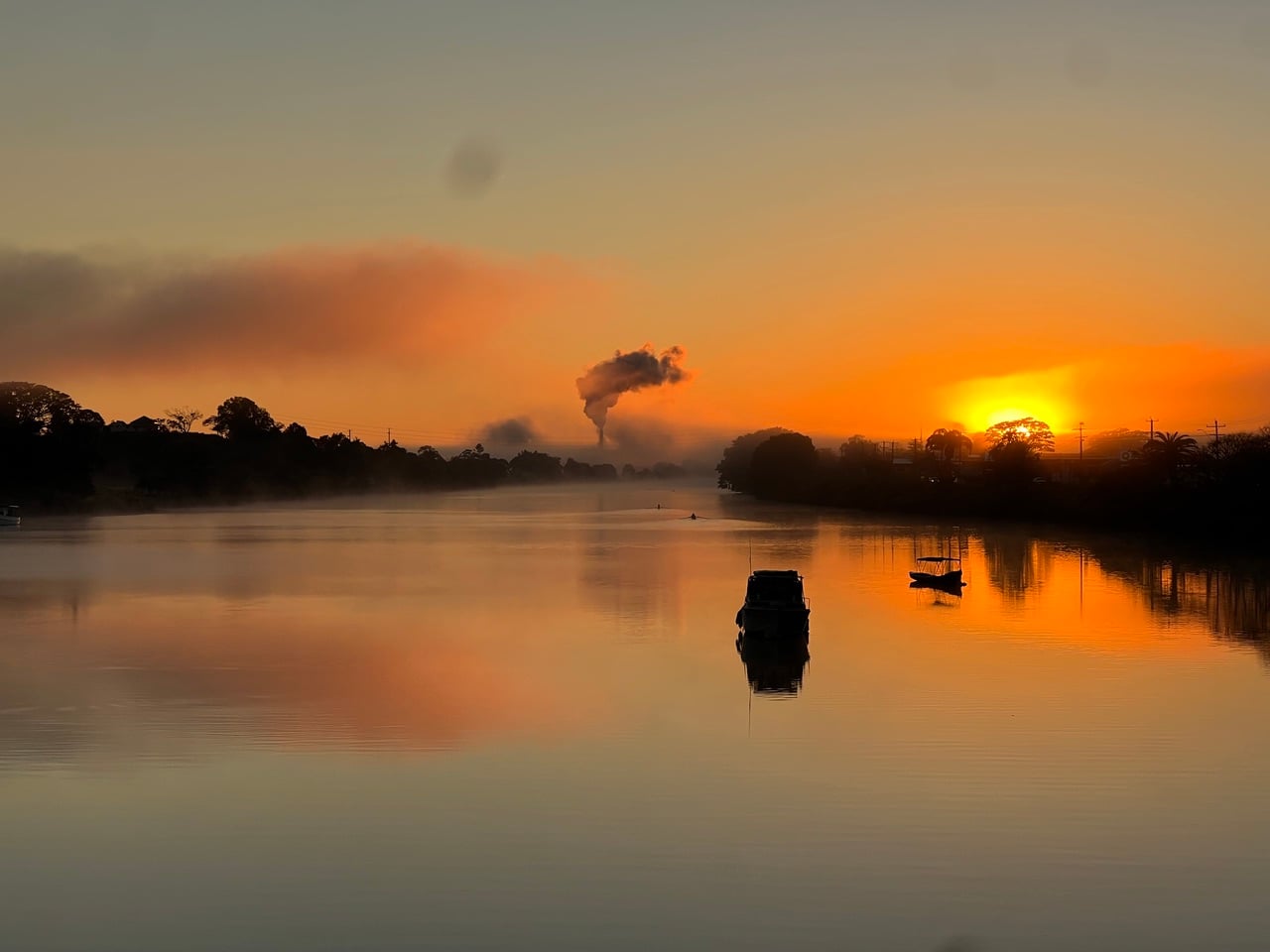 golden sunrise over a river with fog and reflections