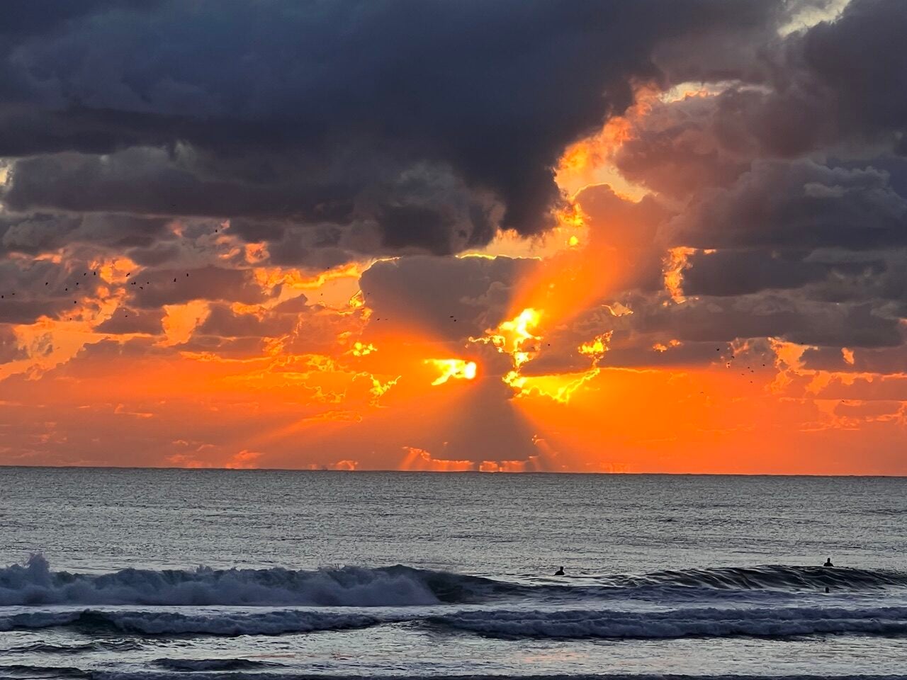 golden sunrise over ocean with light breaking through clouds
